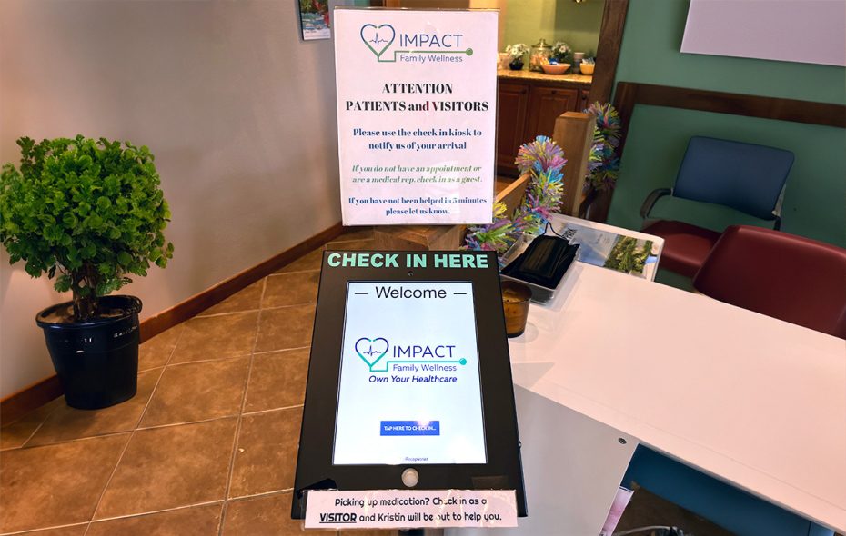 A photo of a sign and an iPad with Impact Family Wellness logo on it