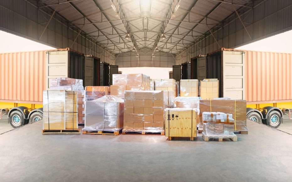 A logistics warehouse with trucks on either side and many pallets of product in the middle